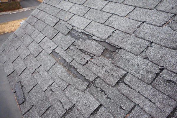 A roof with shingles that have been cracked and broken by hail