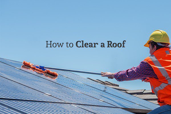 A worker in a reflective vest with a hard hat sweeping off a roof under the words "How to Clear a Roof"