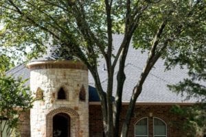 Close up of a new roof on a beautiful house surrounded by trees.