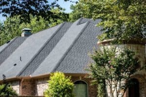 Side angle of a new roof on a beautiful house with nice landscaping.