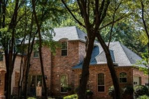 Side angle view of a two-story red brick home with a new roof.