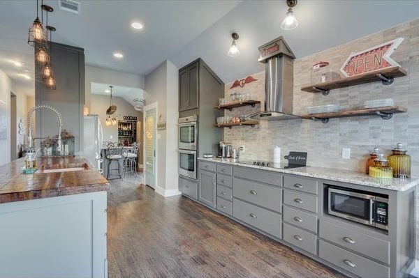 Kitchen remodel with grey cabinets, while tile back-splash, new light fixtures, and hardwood floors