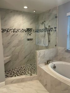 a remodeled master bathroom with new white and black tiles in the shower