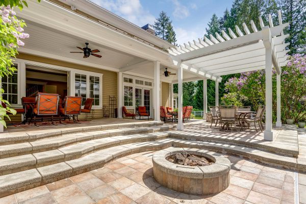 A pergola attached to a covered patio to create a shaded sitting area.